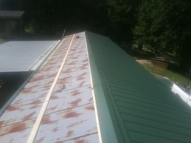 Old rusted panels beside newly installed green metal roofing — Wind Damage Roof Repair by Roofing Brothers in Grovertown
