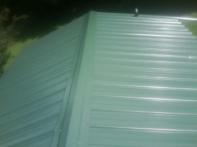 New green metal panels meeting at the ridge of a roof — Flat Roof Repair work by our crew in Grovertown