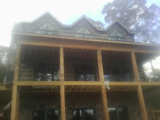 Dormers and porch framing on a large log home under construction — Roof Coating work by our crew in Grovertown