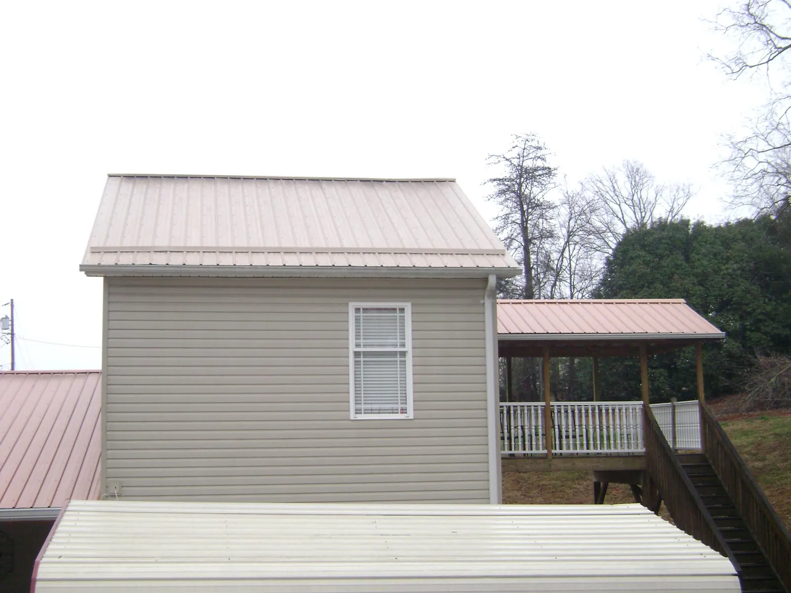 Tan metal roofs on a two story addition and attached porch, from a Roof Replacement job in Grovertown