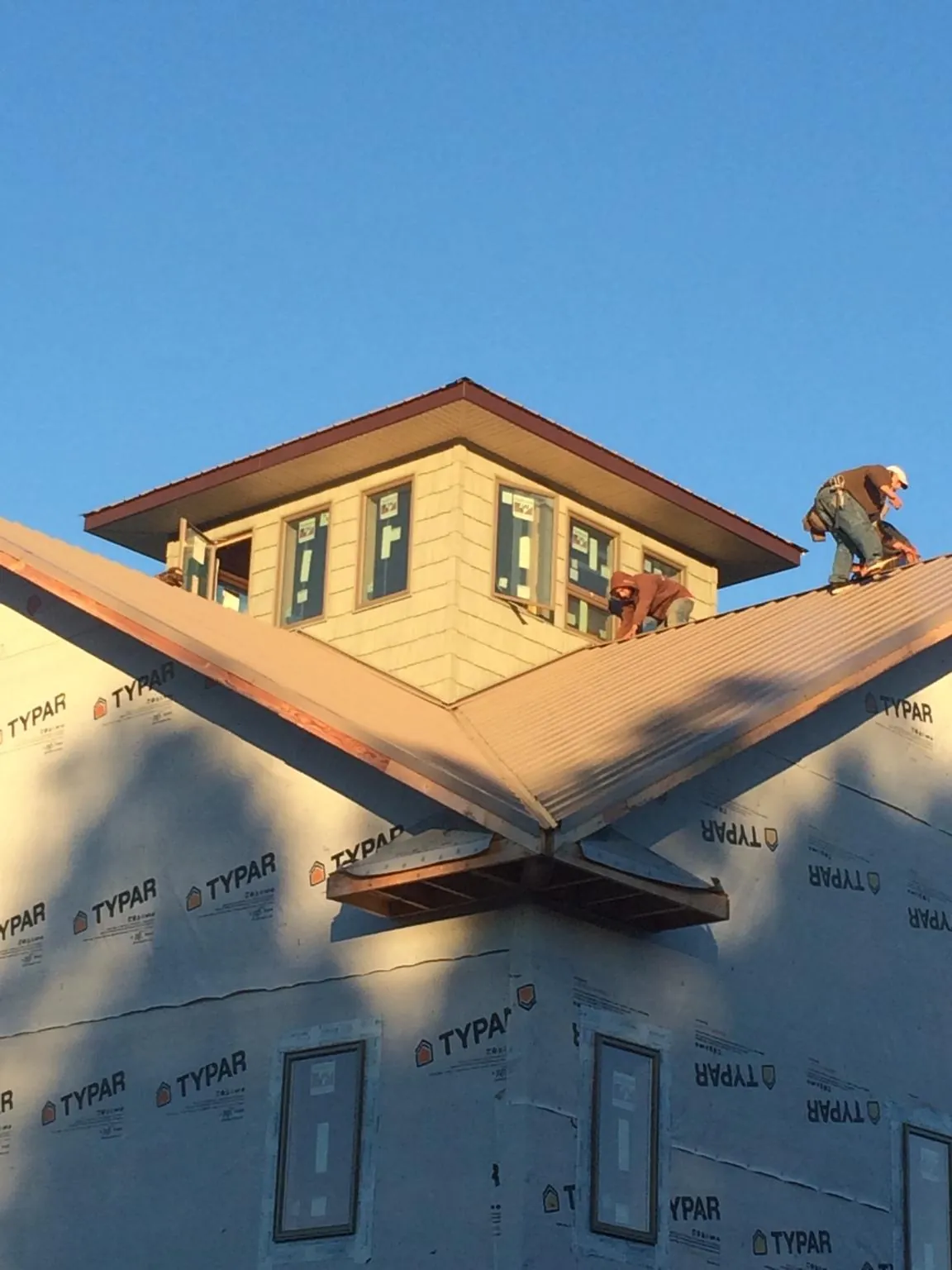 Roofers working around a rooftop cupola on a new metal roof at sunset — Roof Waterproofing in Grovertown by Roofing Brothers